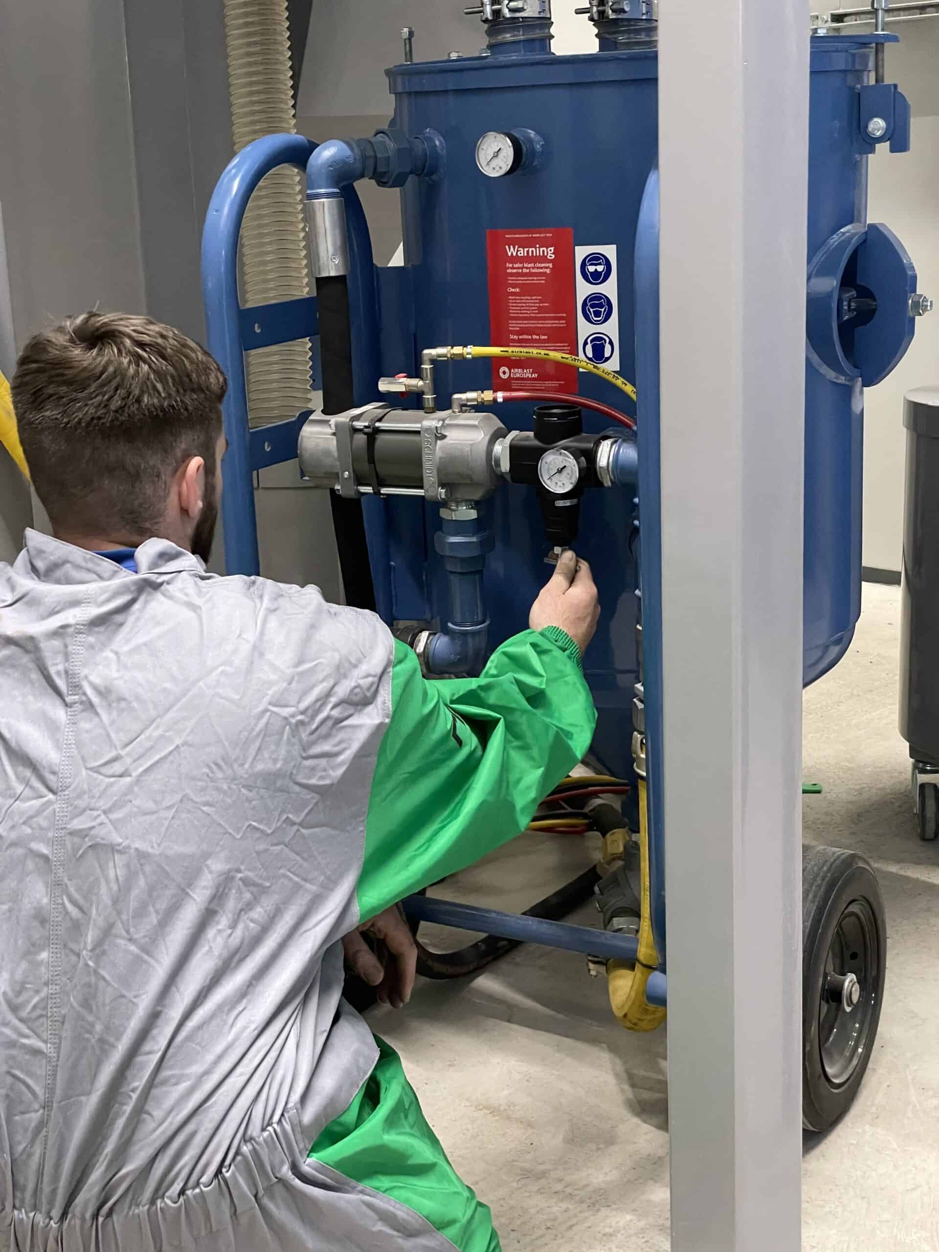 Close-up of an operator adjusting the blast pots pressure inside the abrasive separator room.