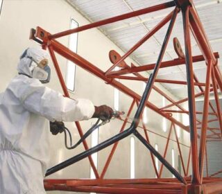 Paint sprayer in a spray room spray coating a steel structure.