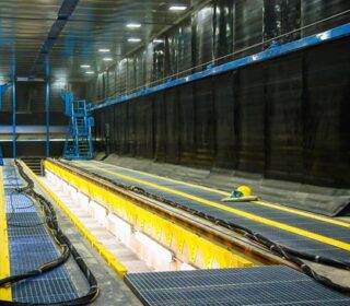 Blast room at bombardier transport (acquired by Alstom, 2021), with a central trench, rails, and moveable access scaffold to process rolling stock.