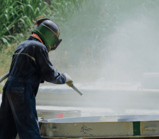 Surface preparation being conducted outside by a man in full PPE