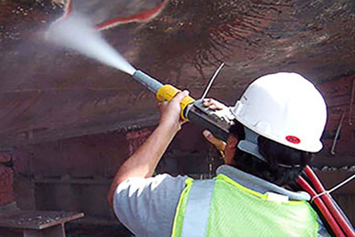 Man water blasting a piece of machinery.