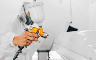 stock image of a spray gun being operated on a piece of vehicle in a spray booth