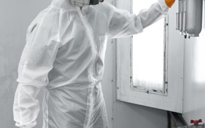 Paint sprayer inside a automotive spray booth in full PPE