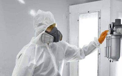 Paint sprayer inside a automotive spray booth in full PPE