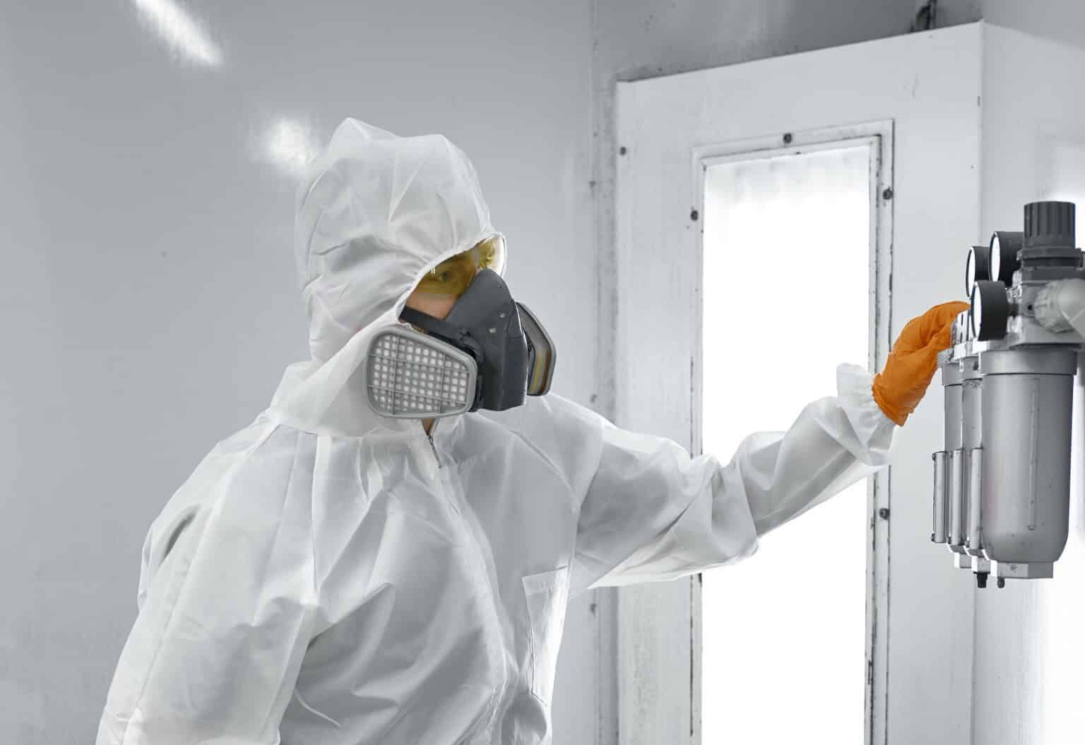 Paint sprayer PPE Paint sprayer inside a automotive spray booth in full PPE