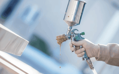 Close-up of a clogged spray gun dripping paint from the nozzle during use.